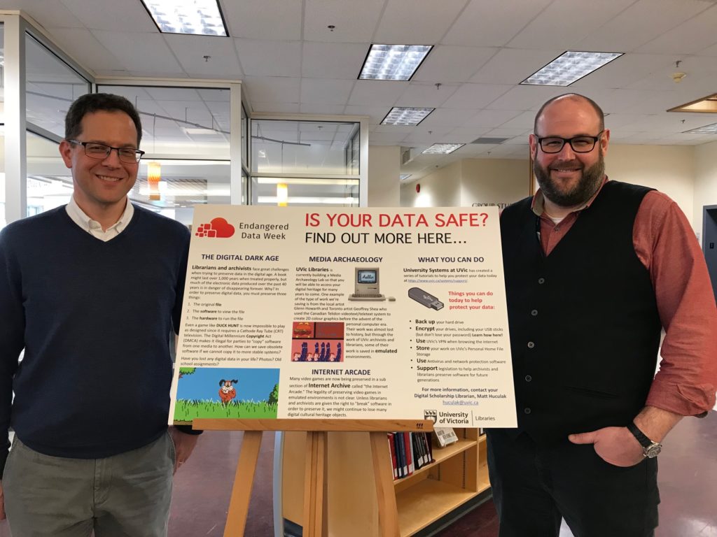 Figure 1: John Durno and Matt Huculak in front of the "Is Your Data Safe" poster