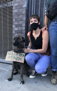 Terra Graziani with her dog wearing a sign that reads "abolish racial capitalism"