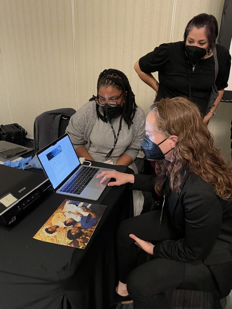 Jennifer Garcon (l) shows workshop participant Anne Ray (r) how to use the lightweight, minimal computing digitization station, as 2022 Forum Fellow Kelley Klor observes.