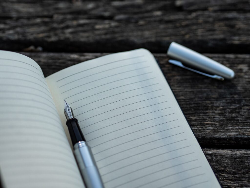 gray and black fountain pen on a lined notebook