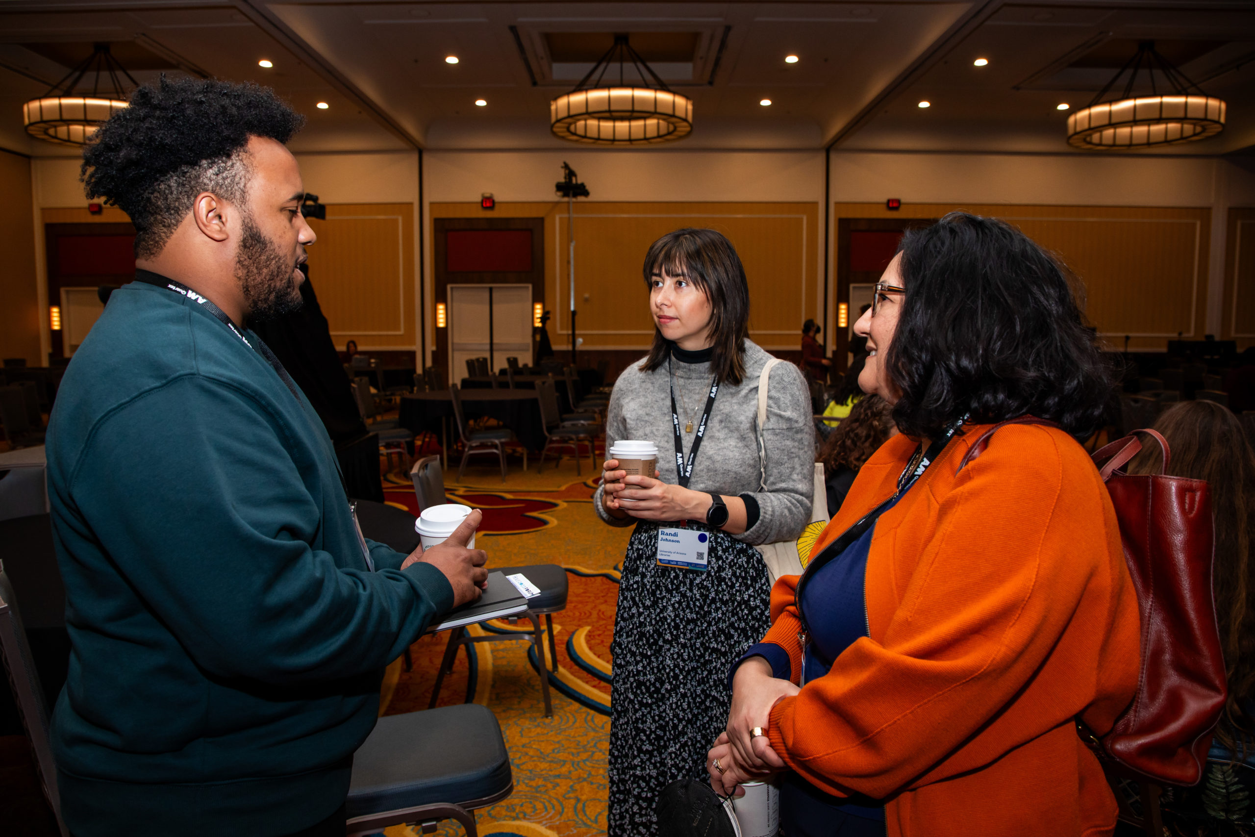 Three people standing and talking in conference venue.