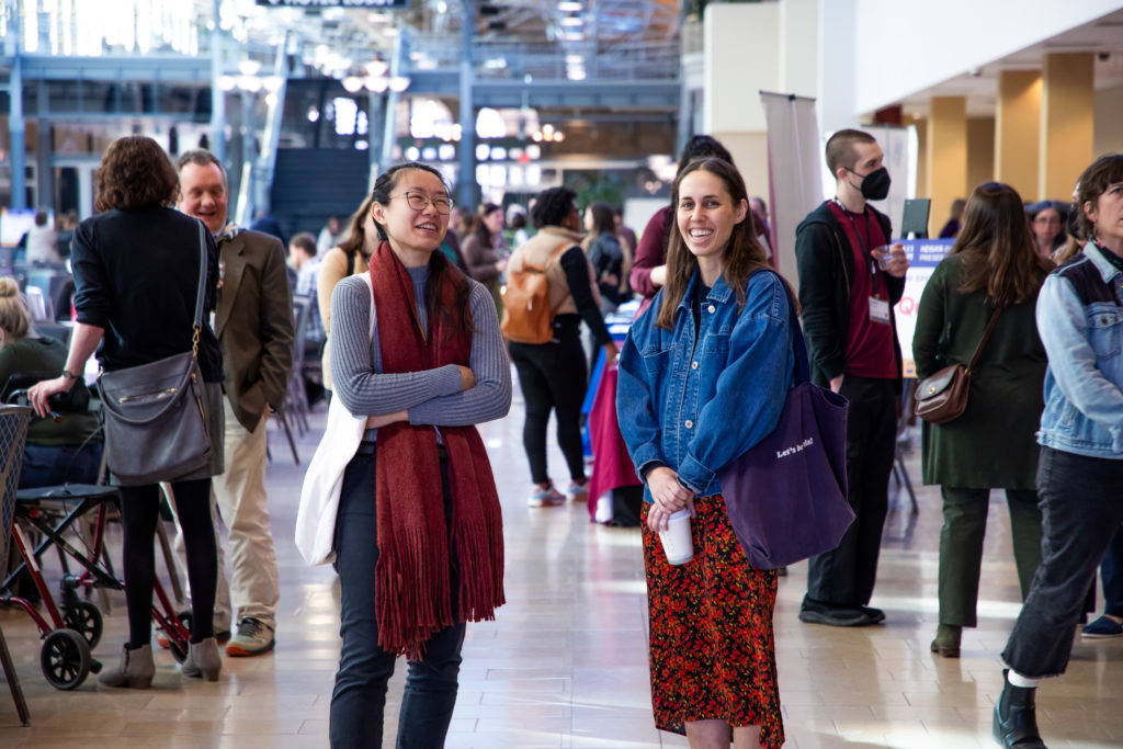 People in hotel hall, mostly focused on two people centered looking at camera