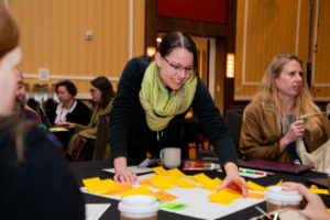 Person reaching over a table with a large sticky note with smaller sticky notes on it