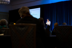 Person at podium presenting to people in a conference room